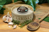 Cheese wheel from 'Fromager des Clarines' vacherin Mont D'or style on a wooden board with garlic and herbs.